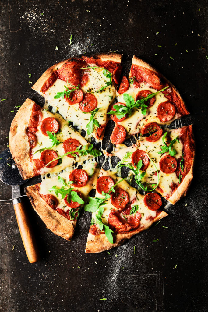 Creative food and drink photography of pepperoi pizza with rocket, styled and photographed in Sussex by a commercial London food photographer and food stylist